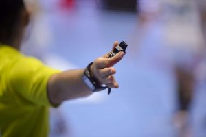 Shallow depth of field with handball referee hand holding a whis